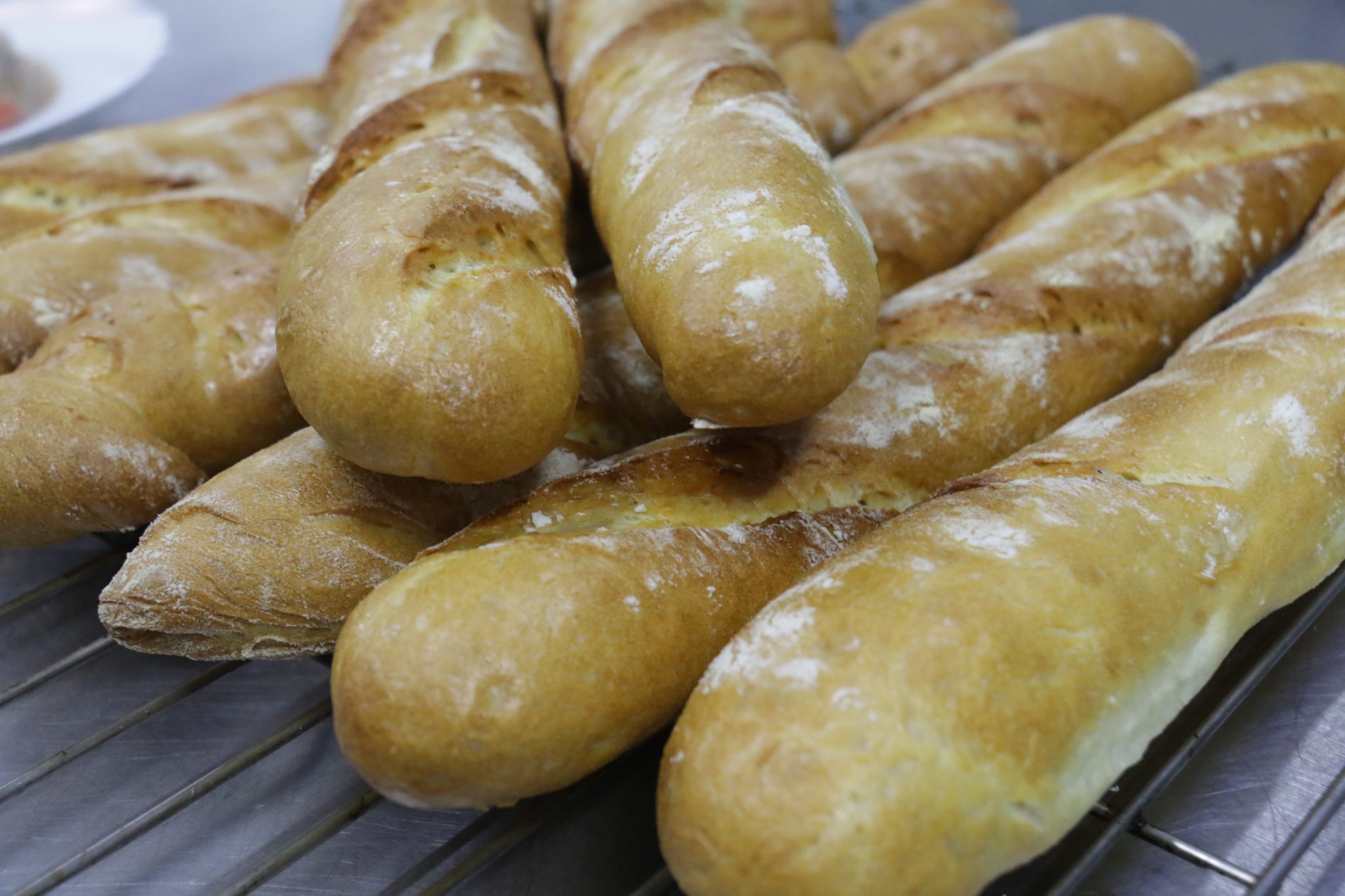 Golden baguettes dusted with flour, side by side on a rack.